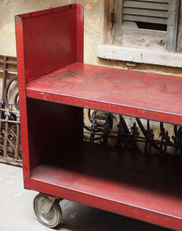The two-shelf rolling cart has appealing worn red paint.