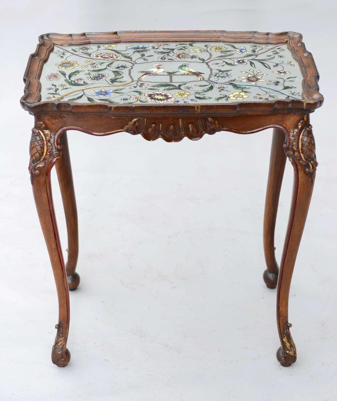 Accent table, having wonderful eglomise top with floral and bird motifs, inset in free-form molded frame, its finely carved apron raised on cabriole legs with stylized pineapples at knees, scrolling toes.

Stock ID: D6578