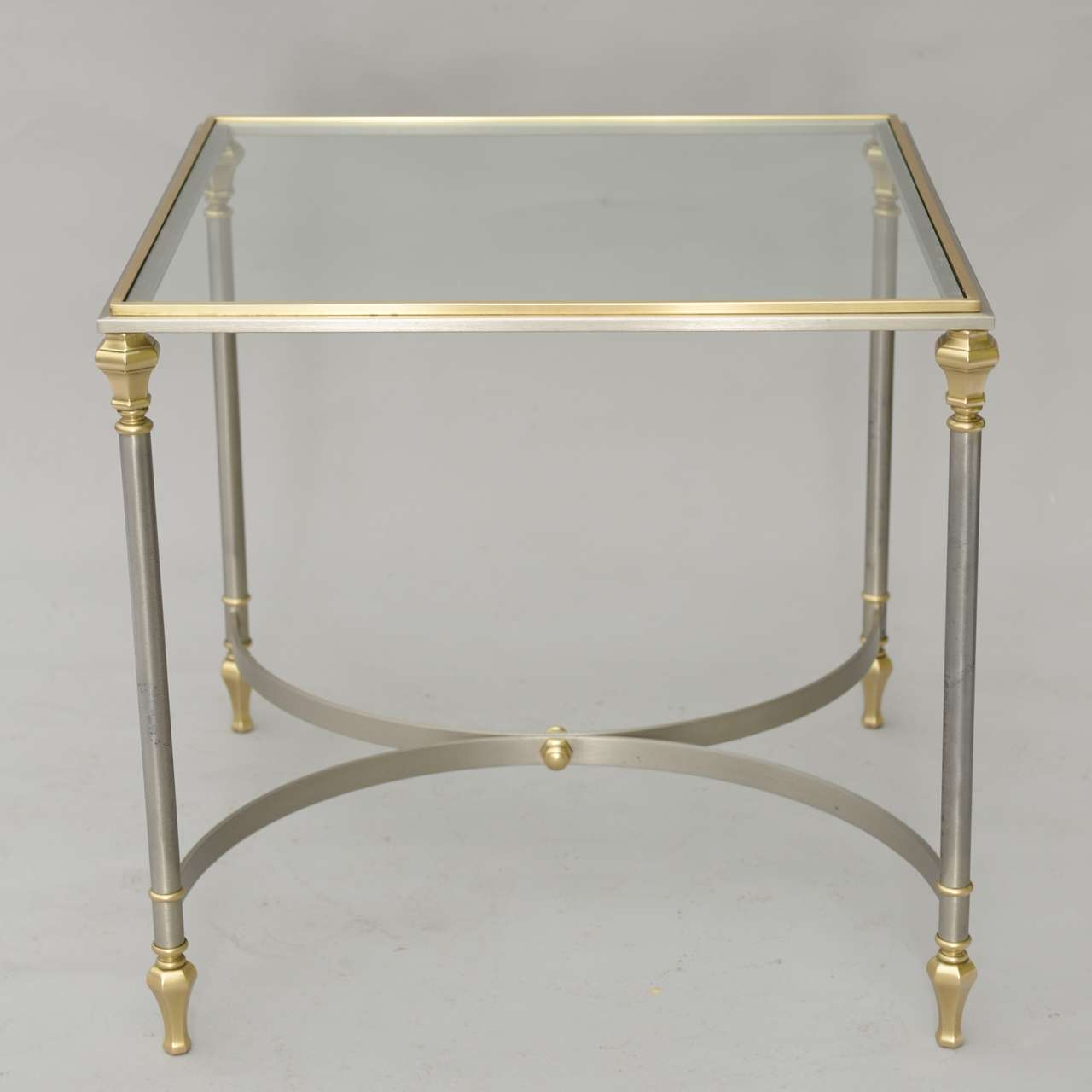 Accent table, of polished steel trimmed in brass, inset with glass top and raised on round legs, joined by bowed stretcher.

Stock ID: D3297