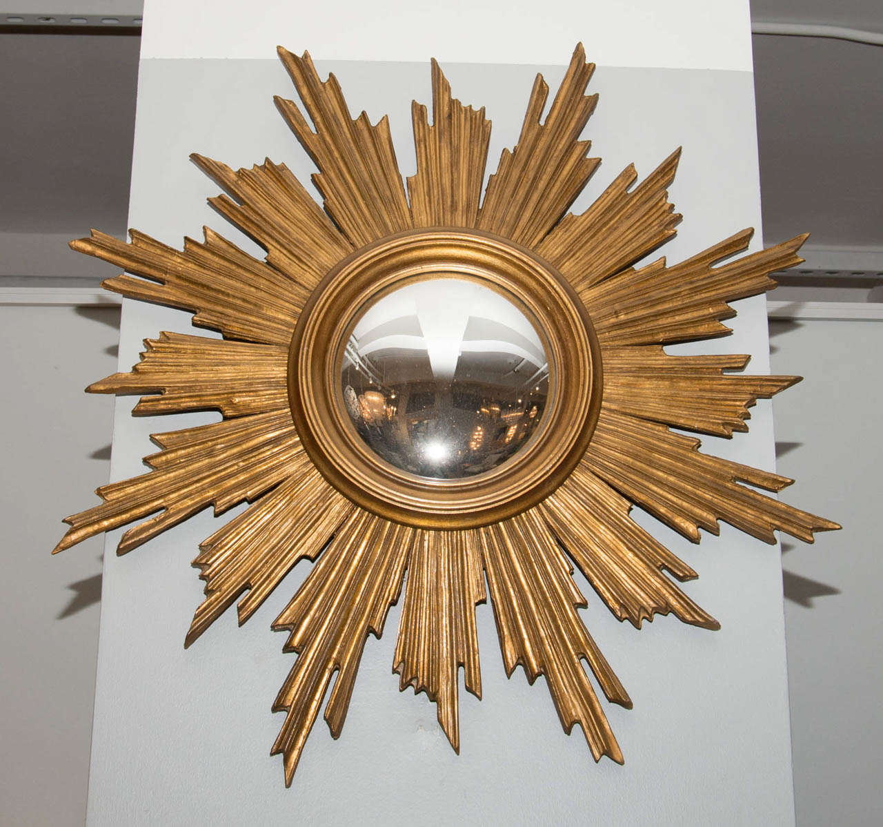 A striking sunburst mirror with a molded center ring and convex glass.