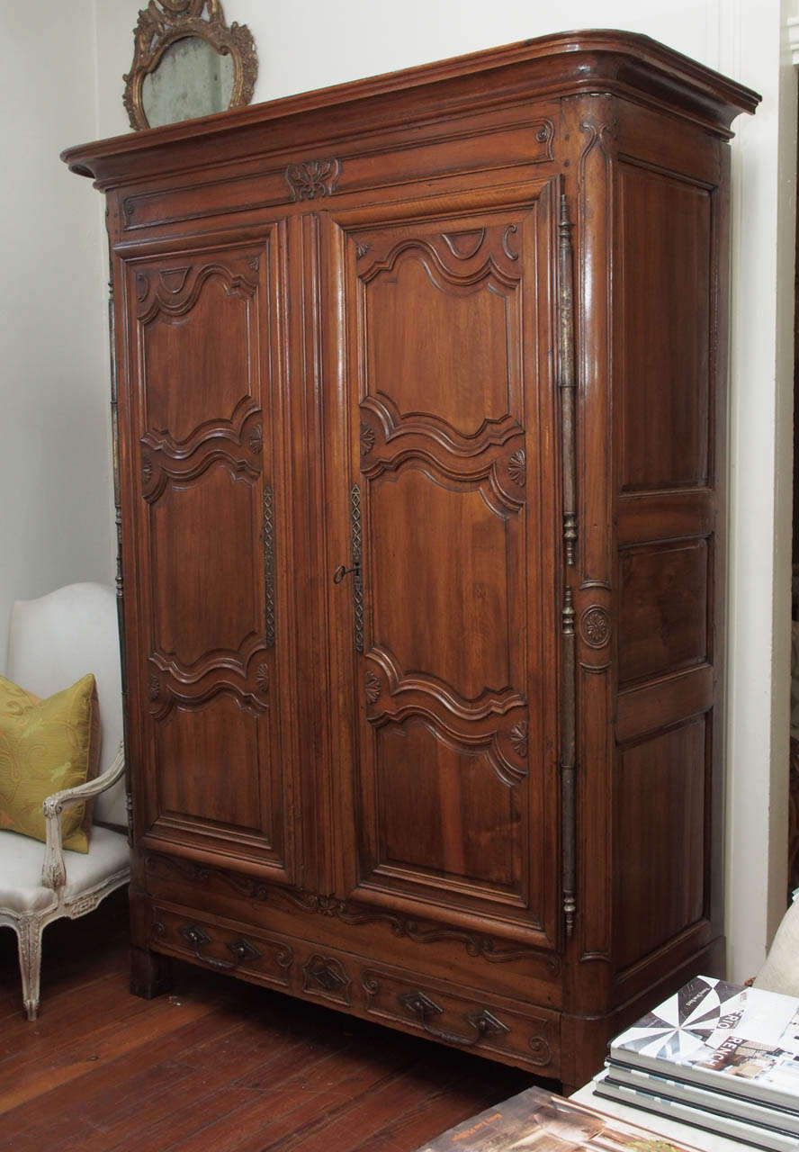 Beautiful walnut early 19th century armoire with a bottom drawer  and 3 small inside drawers. Exceptional original hardware including inside iron sliding key to lock one door panel. Excellent patina.