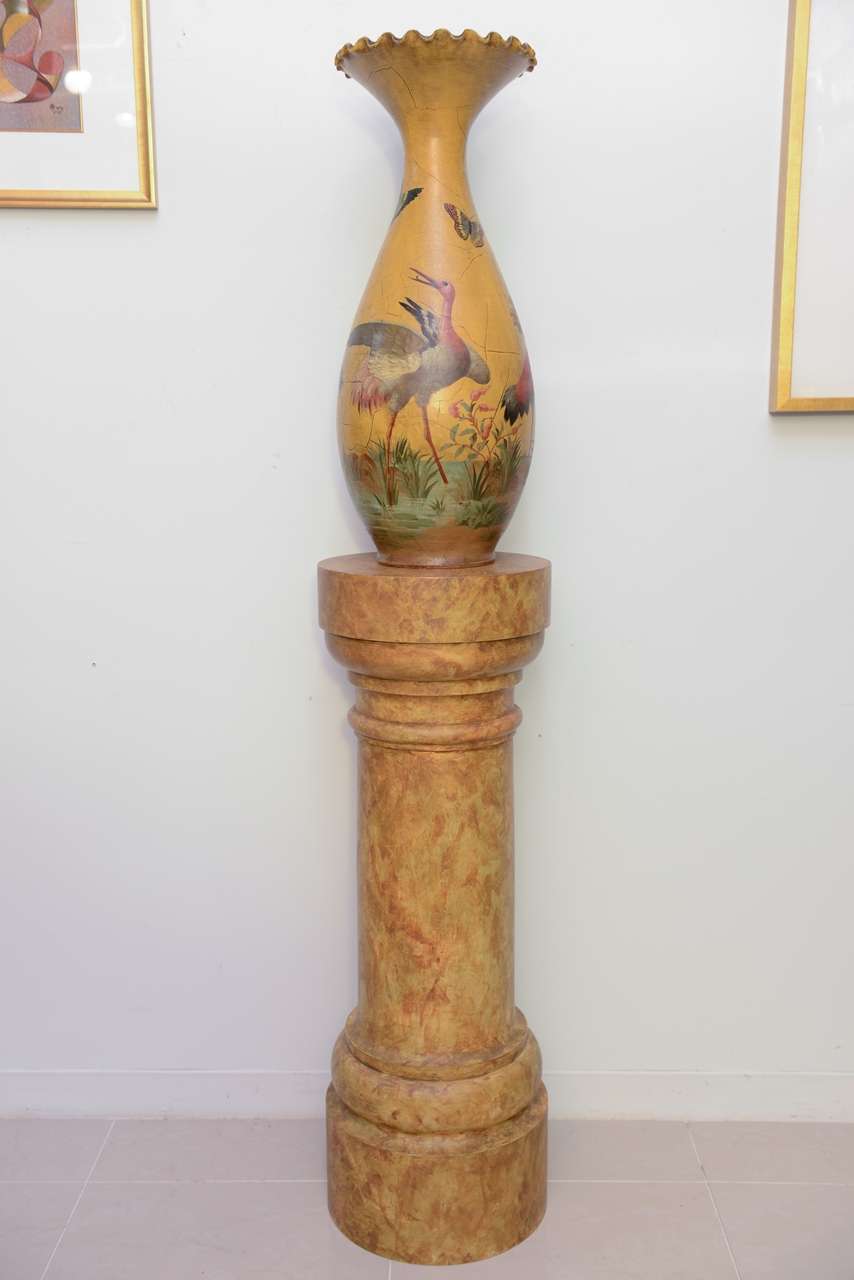The terra cotta urns decorated with mustard ground and water birds and butterflies, on faux marble decorated pedestals.