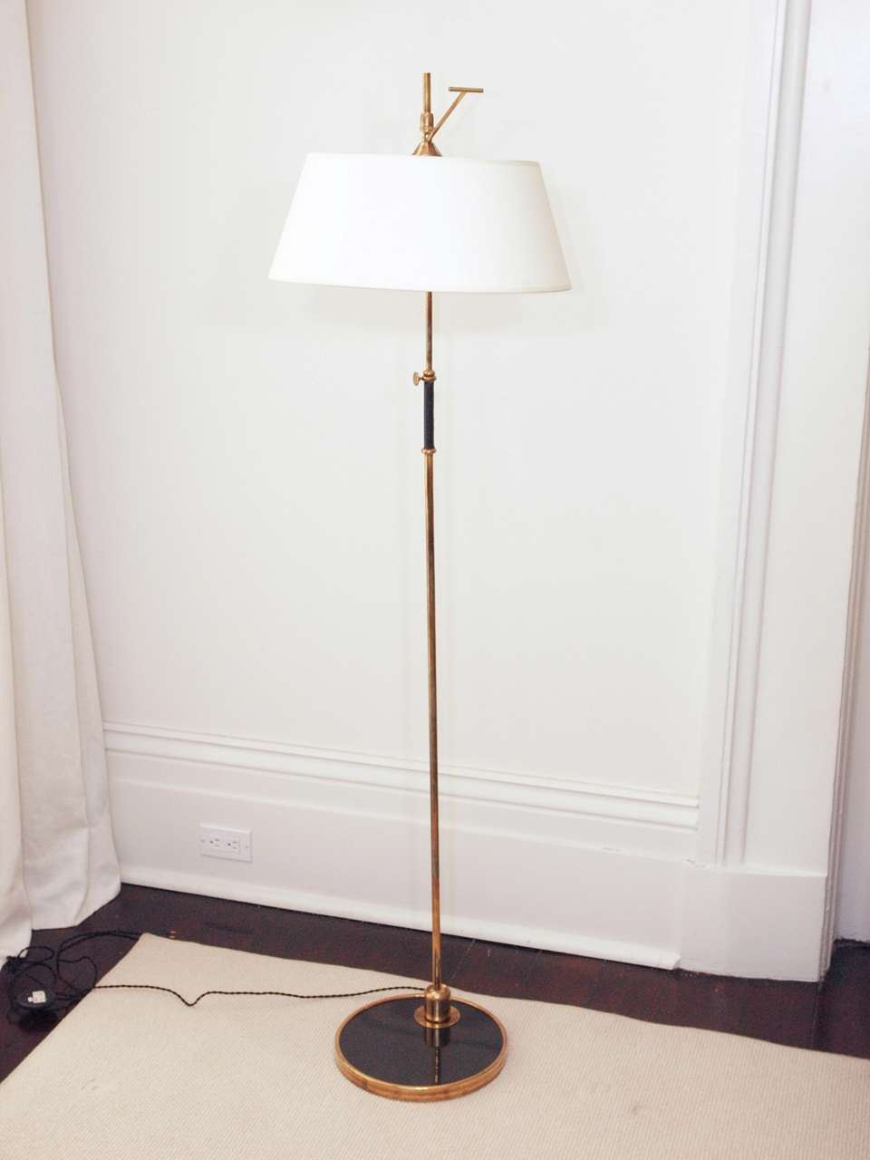 Adjustable one-light floor lamp in bronze with original heavy paper shade; height adjustable by set screw at the stem; tilts forward by ball-joint at the base; shade adjusts by handle at the top; original socket accepts B-22 bayonet lamp; in-line