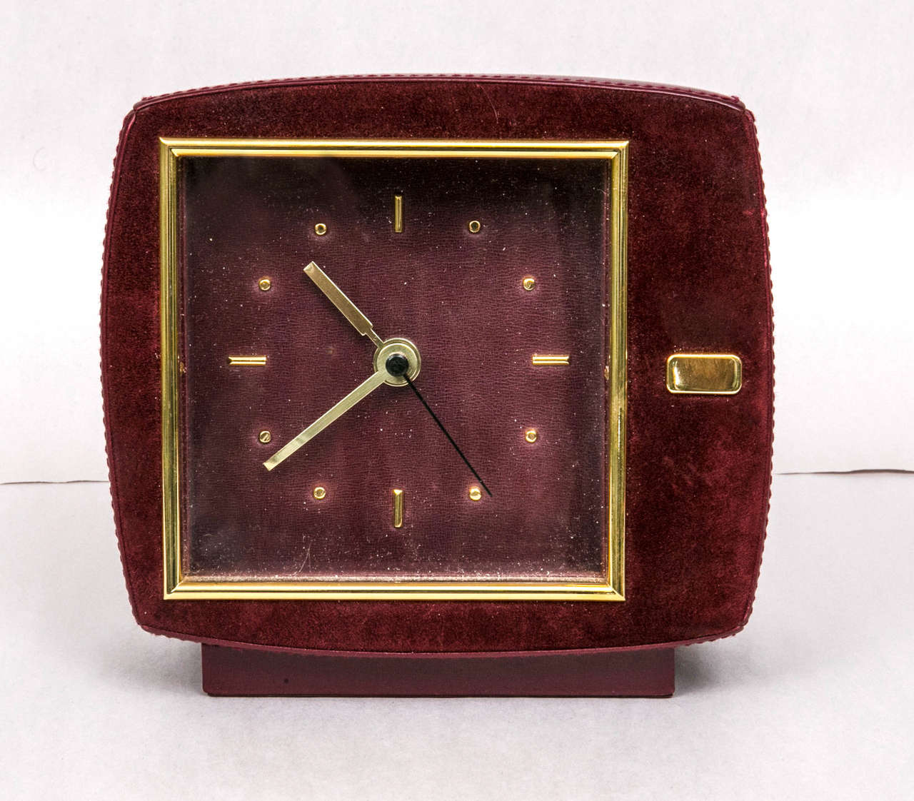 rare mid-century leather and suede clock. opulent burgundy with brass fittings. notable shape and style.