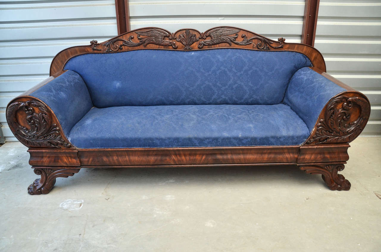 A important neoclassical style claw foot and eagle carved appliqué mahogany sofa. The back crest rail is curved having appliqué of twin eagles centered by a anthemion leaf. The rolled bolster style arms have circular carved eagle designs. The bottom