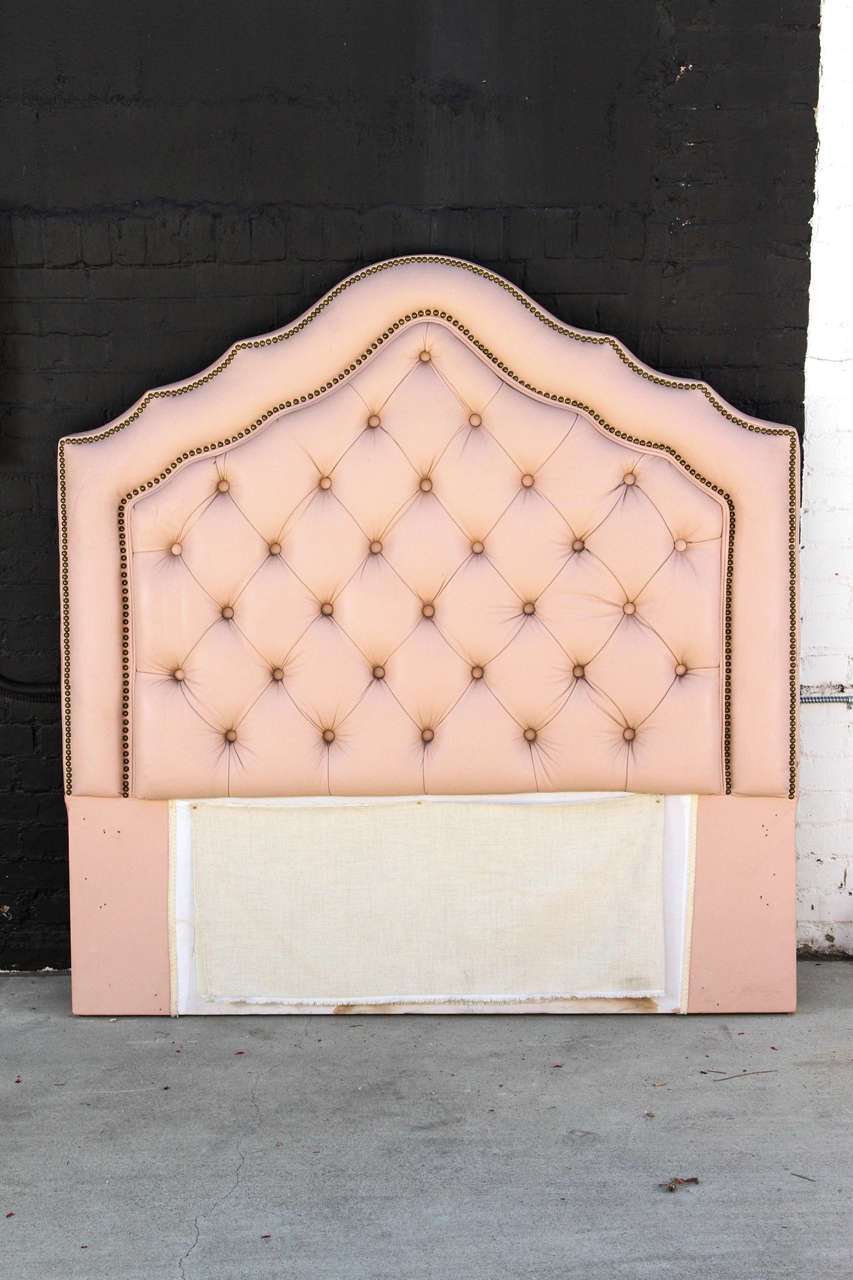 Newly upholstered headboard with tufted blush pink vinyl fabric and brass nailhead detail.