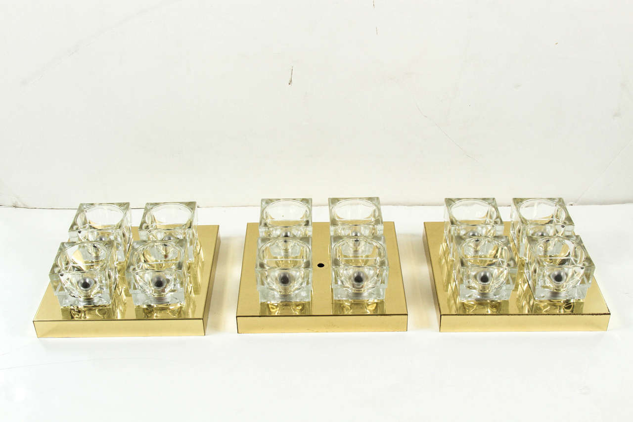 These Mid-Century Modern sconces by Sciolari feature four thick clear ice cubes with inset reflective bulbs affixed to a square brass backplate. Sconces are sold individually.