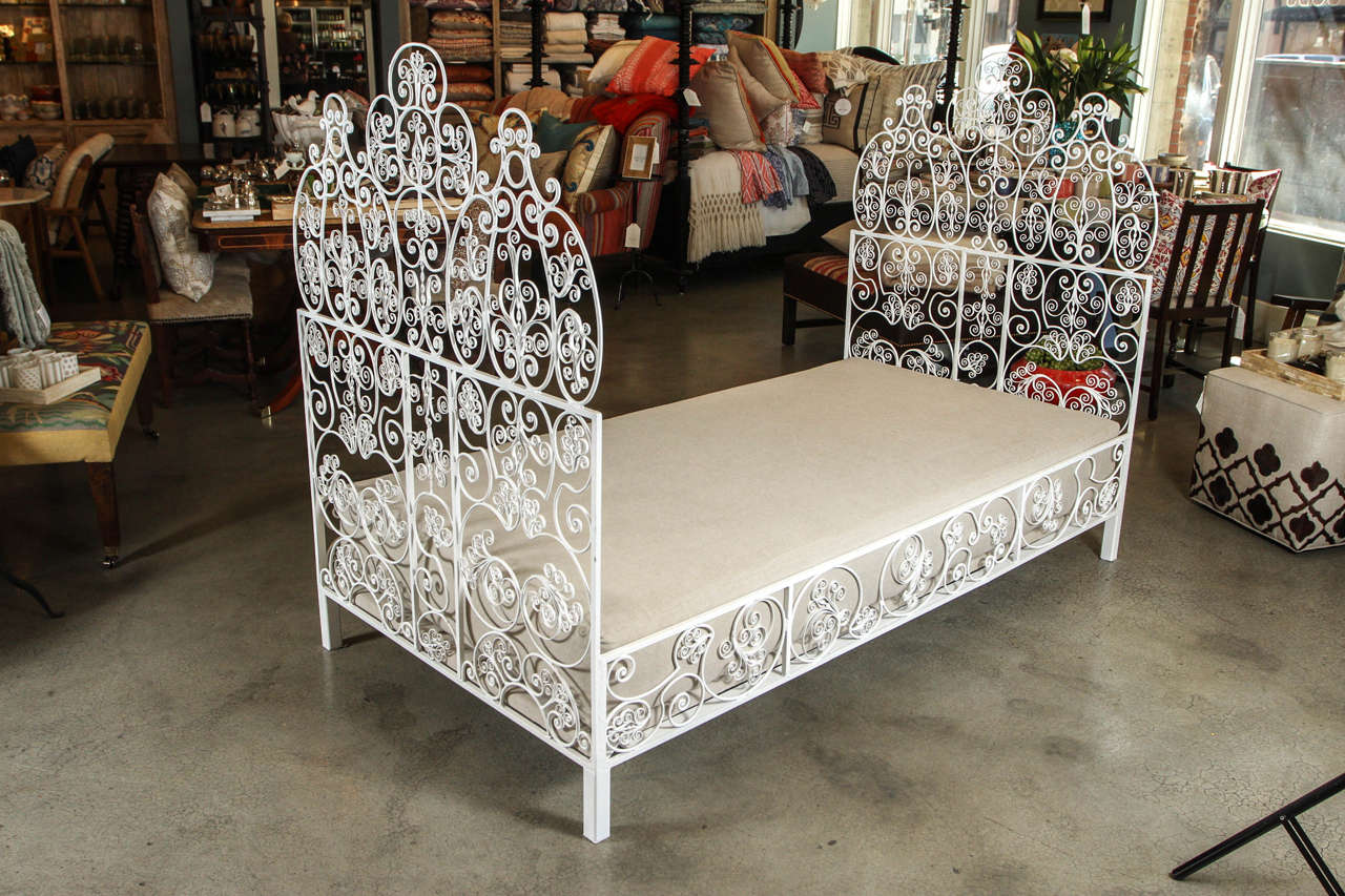 This vintage iron daybed or twin bed features fanciful curls and feminine twists at either end and creates a wonderfully cozy space with its high head and foot. Black iron with a white painted finish and newly made platform and mattress, both