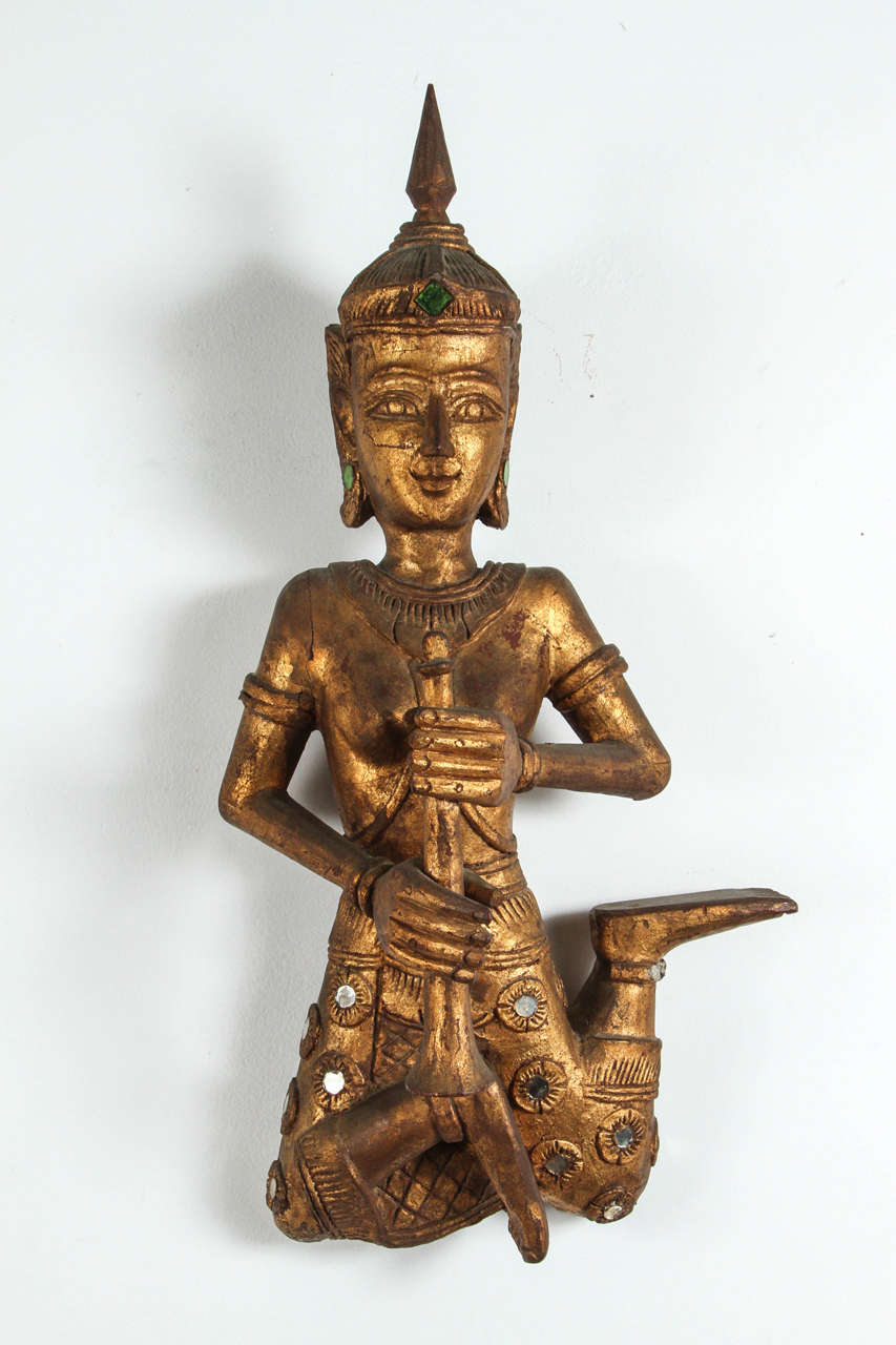 Large pair of Asian Thai figures of Siamese musicians, nicely carved.
Musicians in seated are holding a flute, gilt over red lacquer that can be seen in the back. 
Asian Buddha playing flute in gold gilt adorned with green and clear mirrored gem