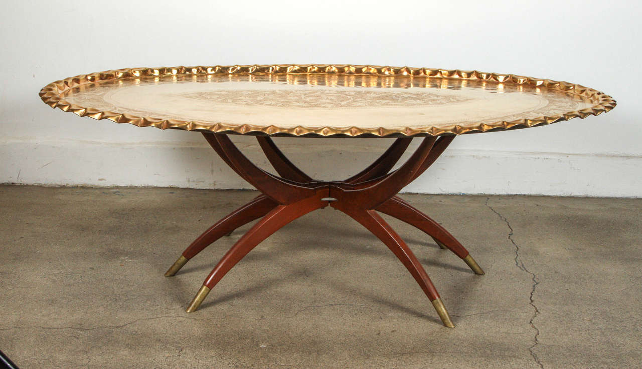 Very large Mid-Century Modern Moroccan oval polished solid brass tray table 54.5" x 36", beautifully hand chiseled and hand-hammered with exquisite Moorish floral and geometric designs and pie crust edging. The tray sits on a folding