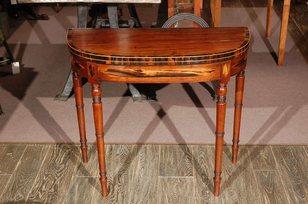 1830s English demilune mahogany game table or console with rosewood inlay banding and inlaid frieze raised on ring-turned tapering legs. Great as a side table, occasional table, or end table.