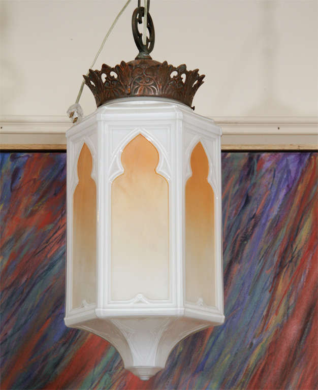 A hanging arabesque pendant chandelier with a milk glass body and vegetal motif bronze cap. The piece has stylized, colored 