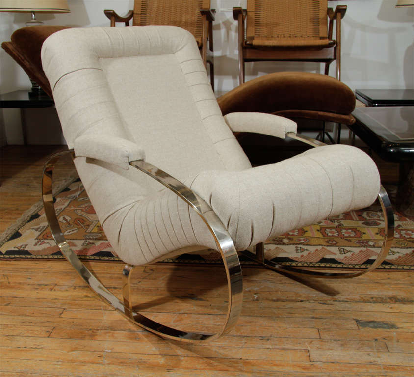 A newly reupholstered chair in light colored tweed with circular chrome rocking legs.