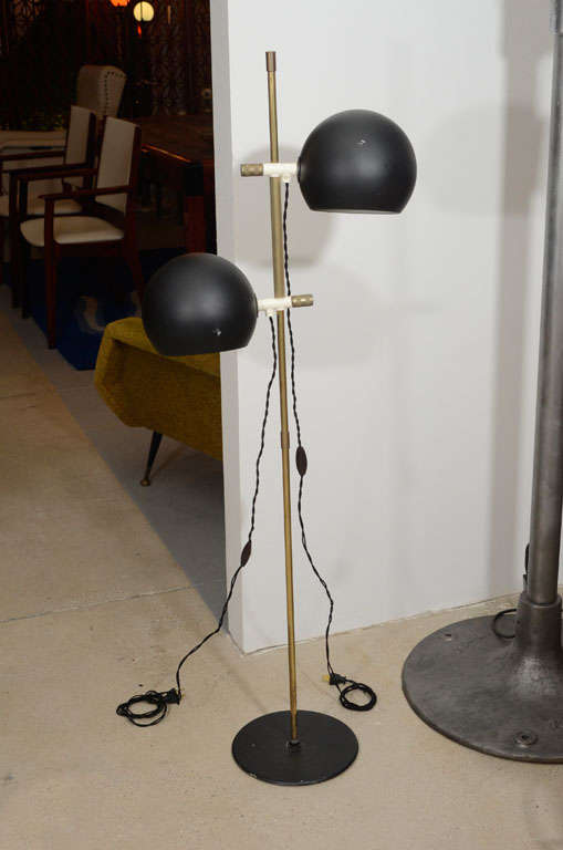 Pair of black metal and brass floor lamps by Hemi Klot.  Sweden, circa 1950.

Each lamp features two globe shades and round bases in black metal, with brass stem.  Rewired with new sockets and French black silk twist cord.  Shades are adjustable