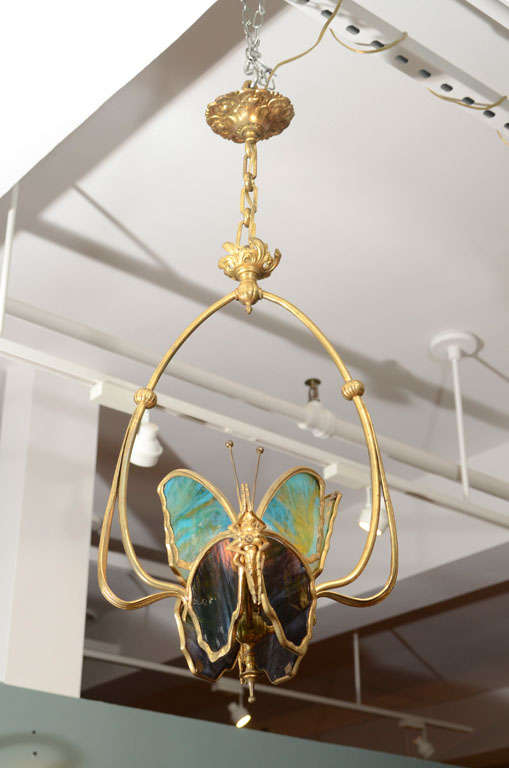 An Austrian Art Nouveau gilt bronze & stained glass Butterfly Chandelier decorated with two butterflies with stained glass panels with in an organic frame.