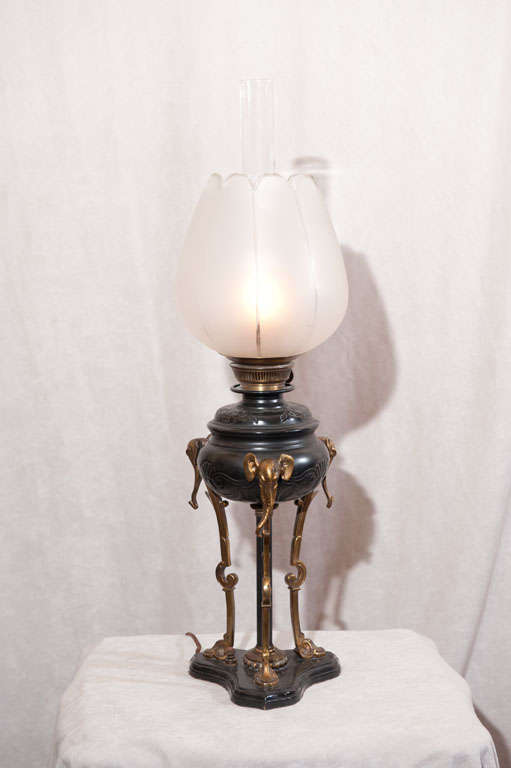 This wonderful, unique oil lamp is quite special.  It has beautiful patina and lovely cast bronze detail.  The shade is original and not a copy.  The base is in exceptional condition, and it has been electrified.  If you like elephants, you will