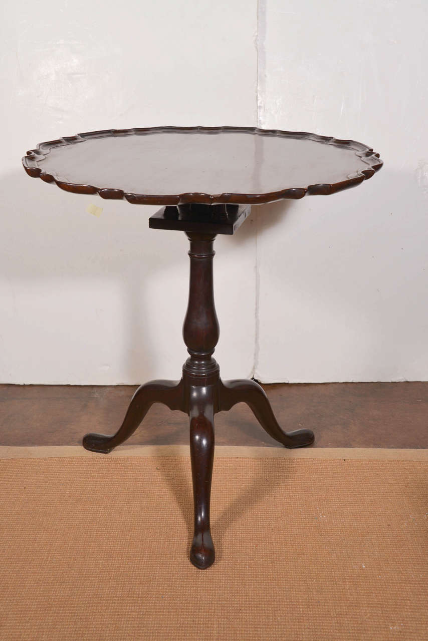 George II mahogany piecrust tilt-top tea table. Circular dished top on a revolving birdcage and baluster support standing on three cabriole legs. Circa 1727-1760.