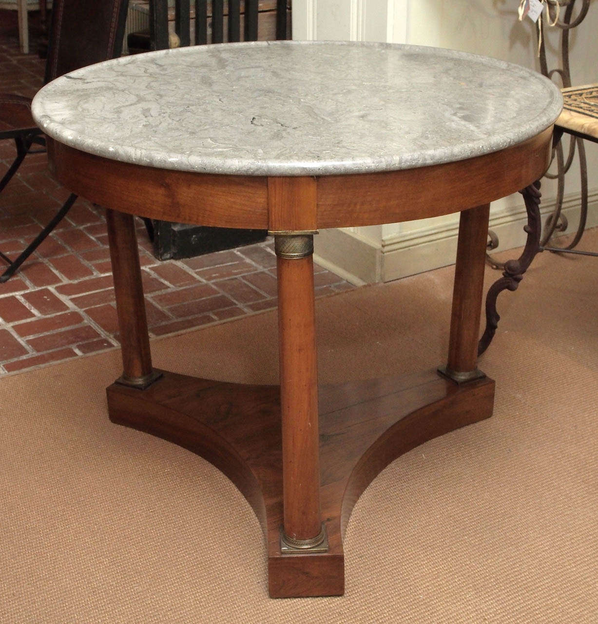 An Empire style walnut gueridon with grey marble top and brass accents