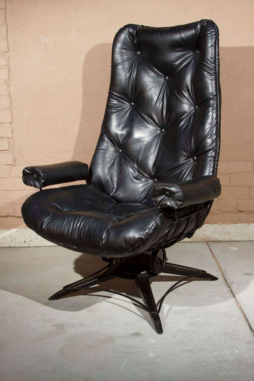 Eames inspired swivel chair with powder coated metal cage frame and tufted black vinyl upholstery.