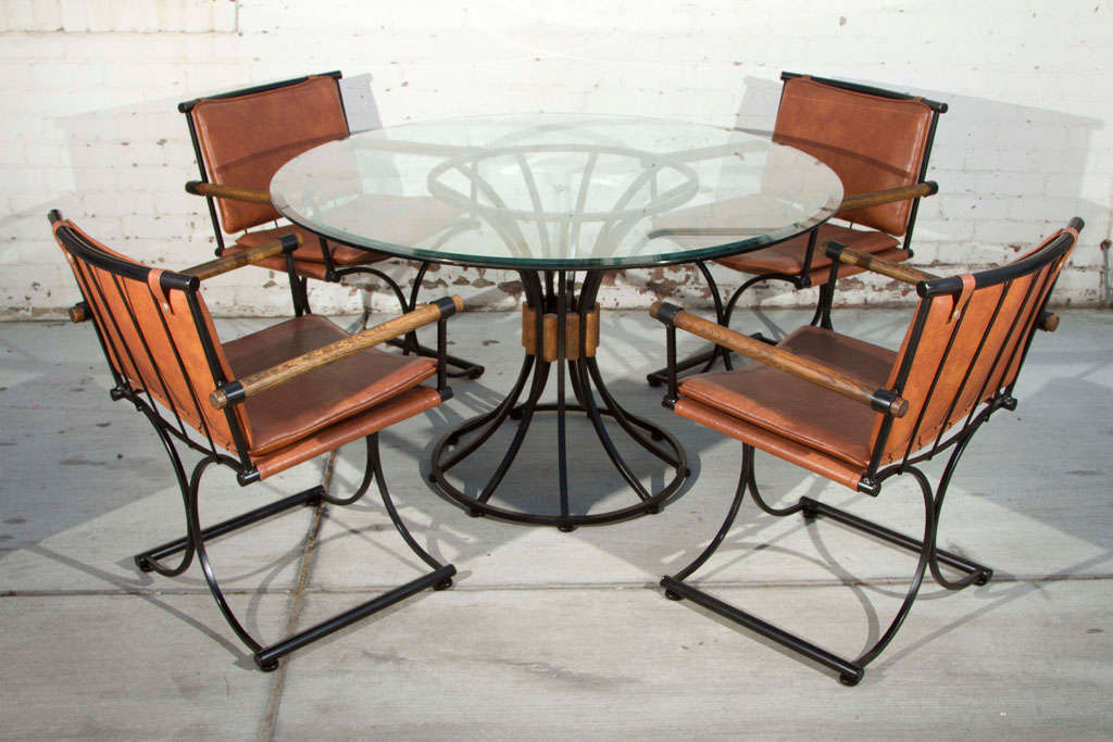 Set of 4 1960's Campaign style armchairs upholstered in brown vinyl with matching glass top table powder coated in a black bronze finish. Original wood details. 

Table: 28