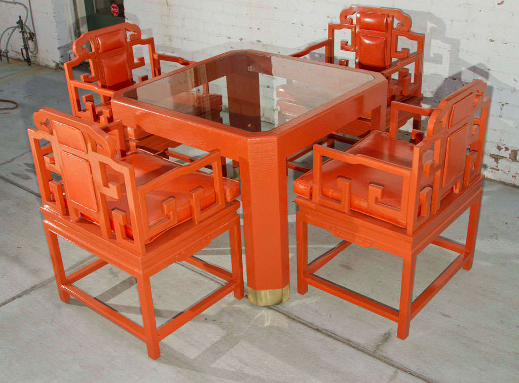 Hollywood Regency chinoserie breakfast or gaming table. New vibrant orange lacquer finish with brass band detailing on table legs. Set of four chairs include Brentano vinyl upholstered cushions. 

Table: 36