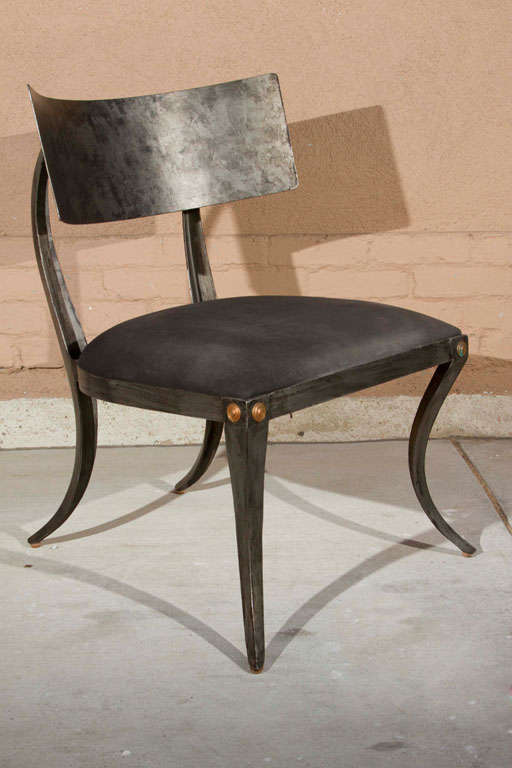Painted sculptural steel klismos style chair with broad back and saber legs and black linen upholstery.