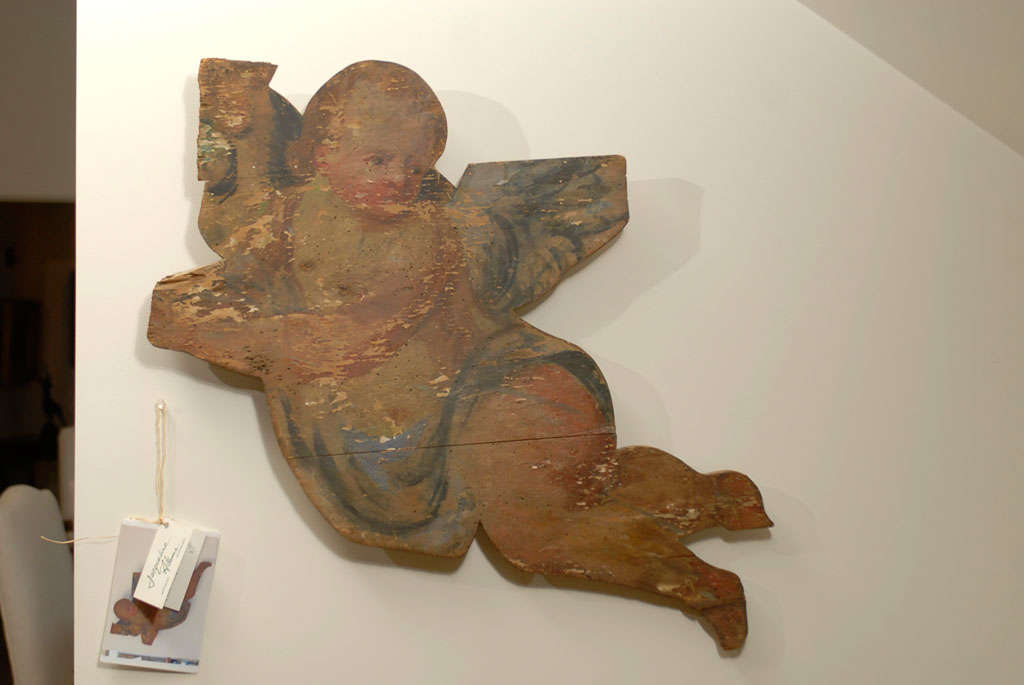 A French painted wood Baroque style flying cherub wall decoration from the 18th century. This French painted wood ornament features a flying cherub that was probably part of a larger composition. The chubby character, dressed on the waist with a