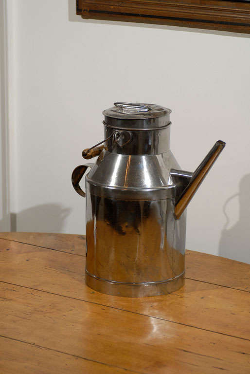 A French metal milk can from the 19th century, with long spout and wooden handle. Crafted in France during the 19th century, this metal milk can features a large oblique spout and rear handle. The circular lidded top showcases a wooden handle