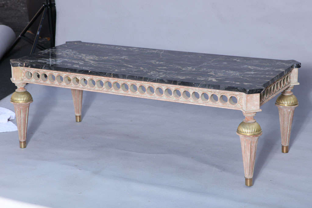 Cocktail Table, having a rectangular top of black portoro marble with squared-corners, on pickled wood base, its apron pierced with stylized guilloche, raised on reeded-brass capped round tapering fluted legs.