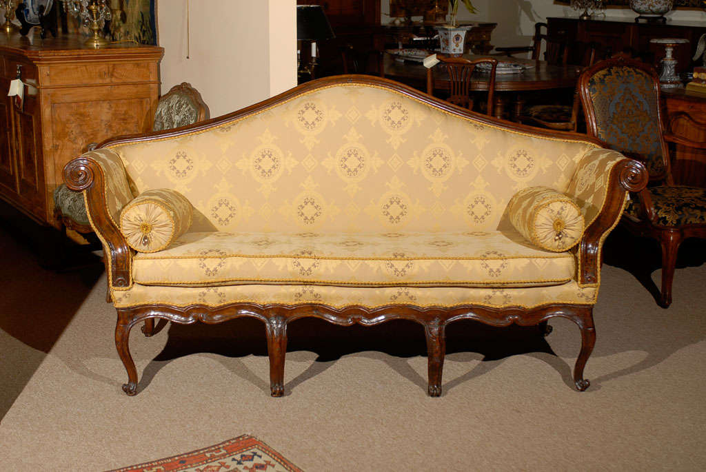 An Italian rococo canape in walnut with arched back, scrolled arms, and shaped apron. All resting on curved legs and cabriole feet. 

For many more fine antiques, please visit our online gallery at: WWW.WILLIAMWORDANTIQUES.COM.
William Word Fine