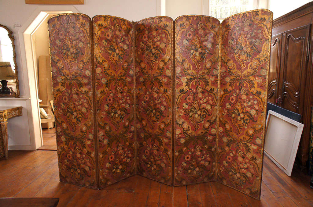 Fine 18th century Italian five-panel embossed, painted and parcel-gilt leather screen. Each panel with painted flowers within gilt cartouches. Edges are finished with gilt tooled leather and nail heads. The back with red leather, gilt scrolls,
