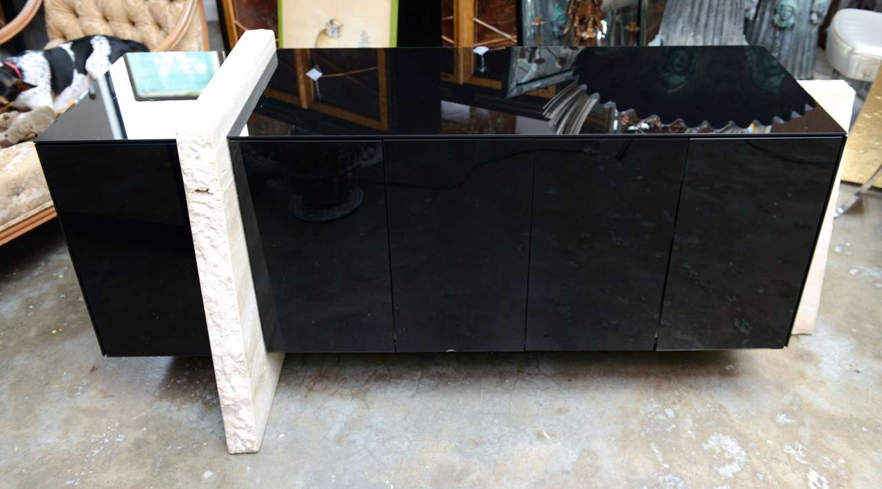 Chic floating black glass console with travertine marble supports.