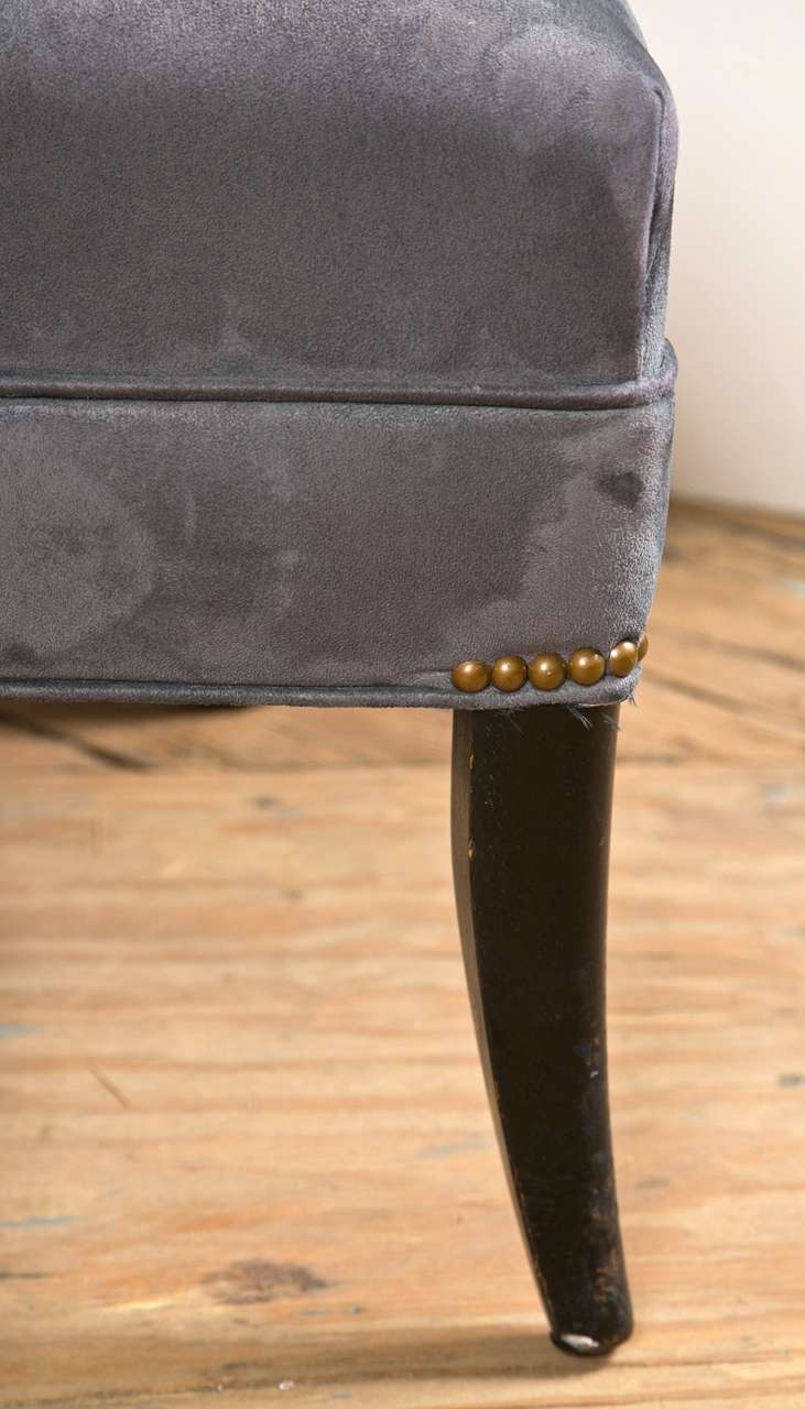 The enonized legs on this chair is flared or tapered while the upholstery is a gunmetal microsuede. Recently recovered.  There are nickel nail heads above legs.  Spring construction verifies 1940's time frame.  Coiled sprung with burlap straps for