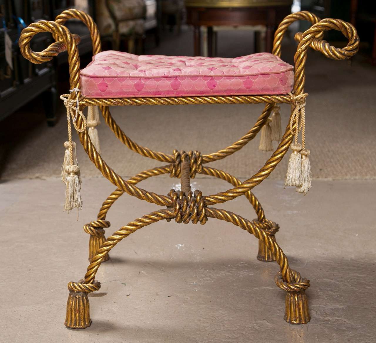 A wonderful pair of Italian gilt tassel form decorated stools. Each made of brass twisted metal standing on tassel knotted feet leading to a double C roped frame. Each cushion supported by a metal tweed seat.
