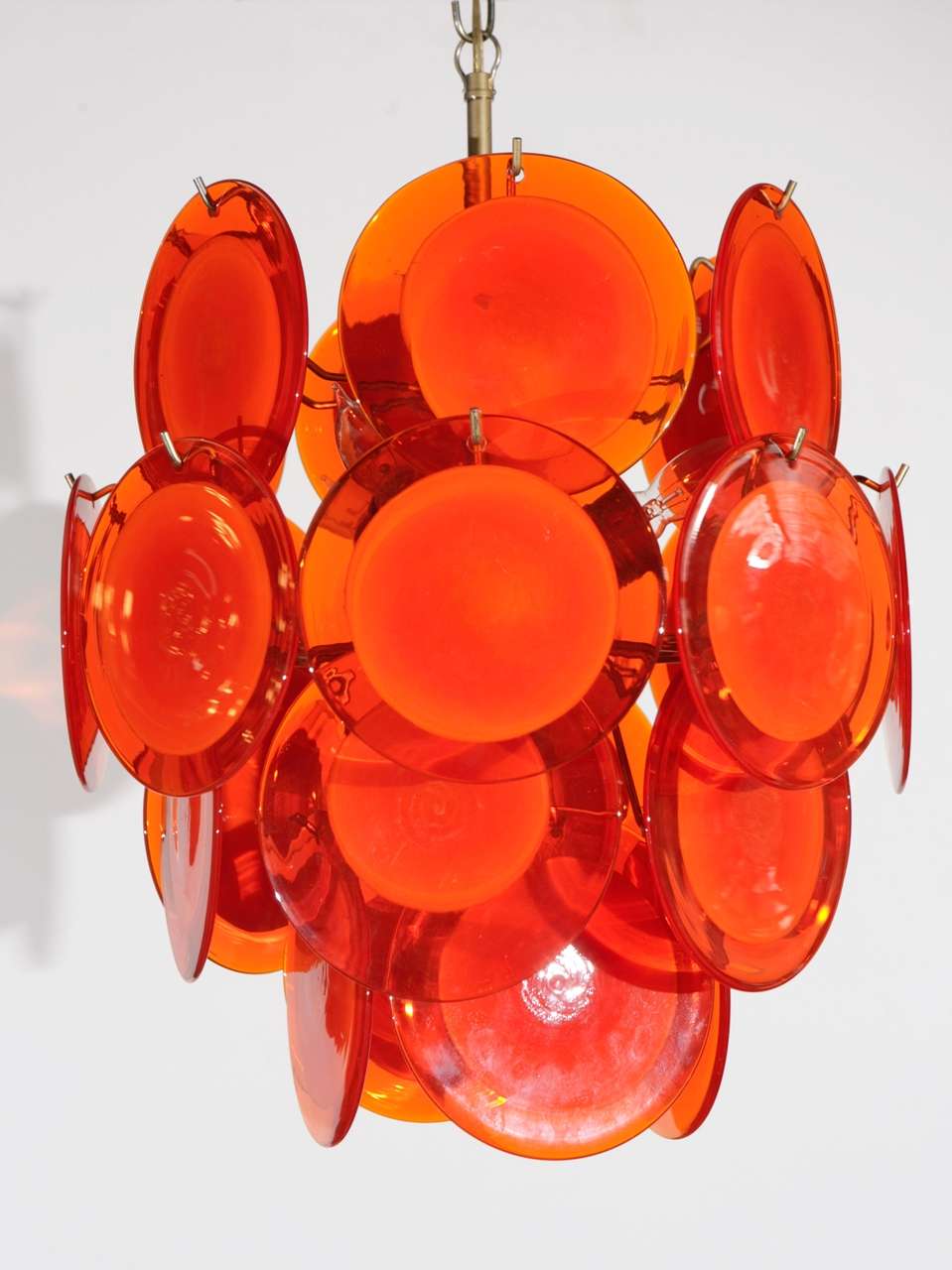 Four tiers of orange handblown glass discs on a gold tone fixture.