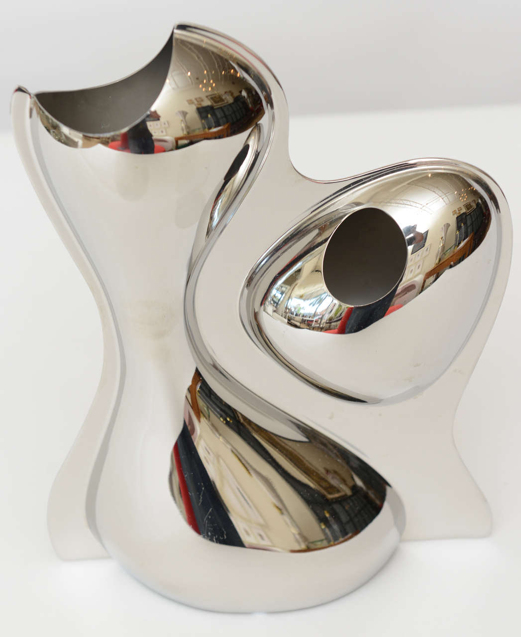 This wonderful artistic and sculptural mirrored stainless steel vase is modernist biomorphic. It is signed Ron arad for Alessi. There are two asymetrical openings for flowers... It has almost a mirrored Anish Kapoor reflective mirrored quality to