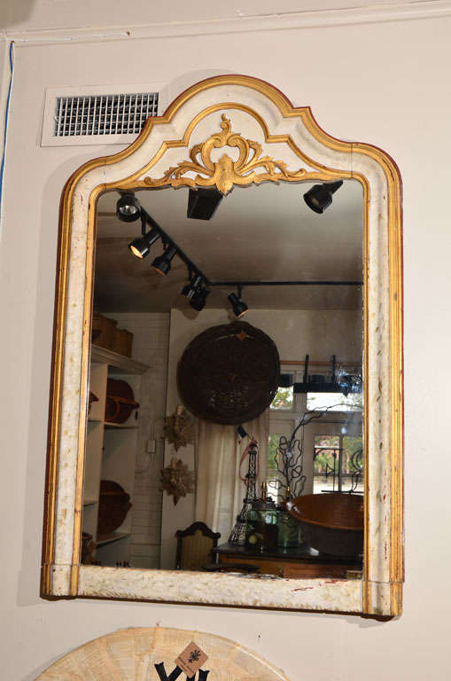 This stunning mirror circa 1850 has a gorgeous arch with a fleur-de-lis and flame detailing. The French flair, patina and gilding are sure to add old world charm and elegance to any space! Frame has been recently reinforced to add extra support.