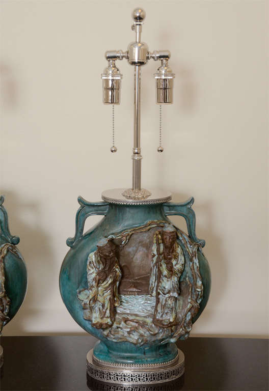 This pair of ceramic lamp bodies which have an Asian scene on one side and a beautiful green glazed finish on the other are signed on the bottom by Fantoni. The lamps bodies are mounted on polished nickel bases and have been newly rewired with