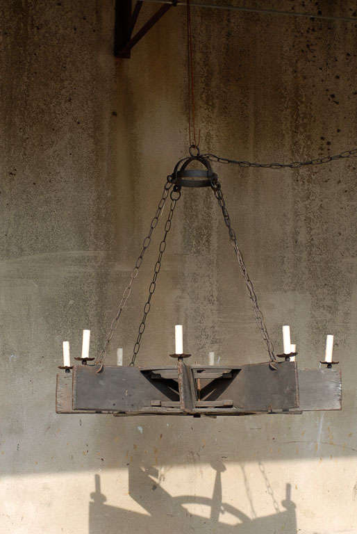 This eight-light vintage hardwood chandelier has been constructed from a paddy water wheel found in Southern India. The wooden boards have been topped with simple looking metal shaped bobèches supporting the painted candle sleeves. Four chains are