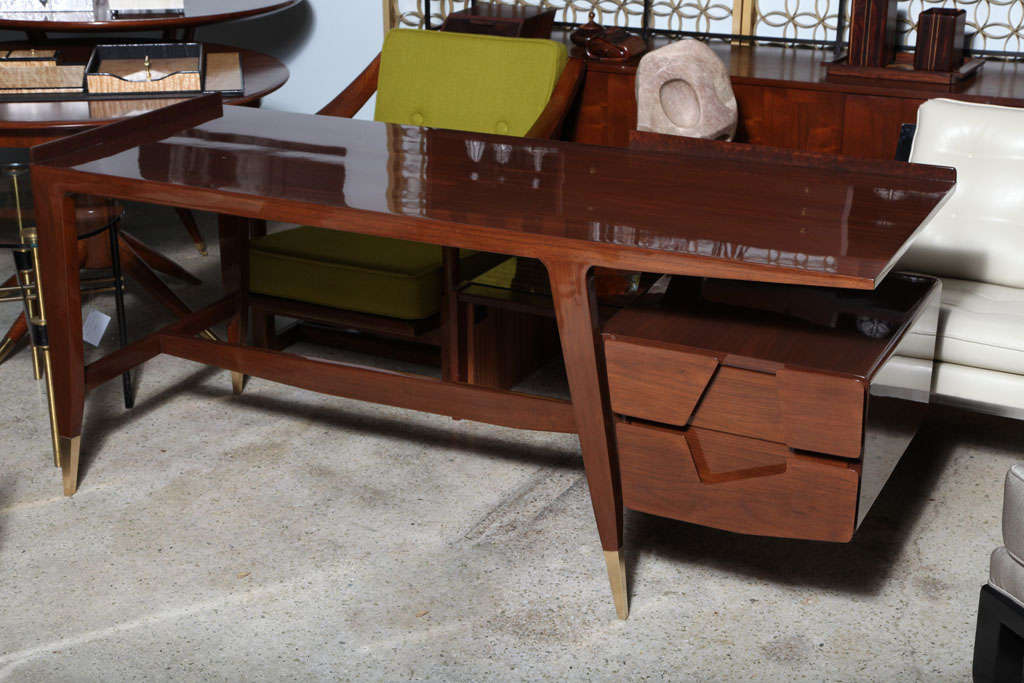 the rectangular top with galleried edge over a bank of drawers with asymmetric cutouts on tapering legs with brass sabots