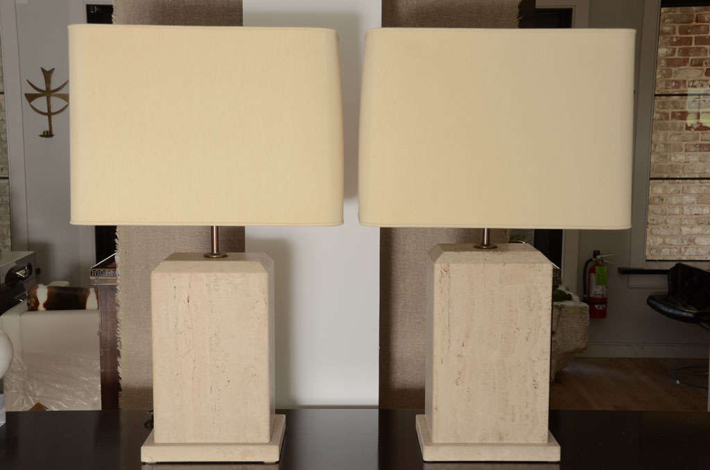 A perfectly proportioned pair of solid travertine lamps with linen shades.