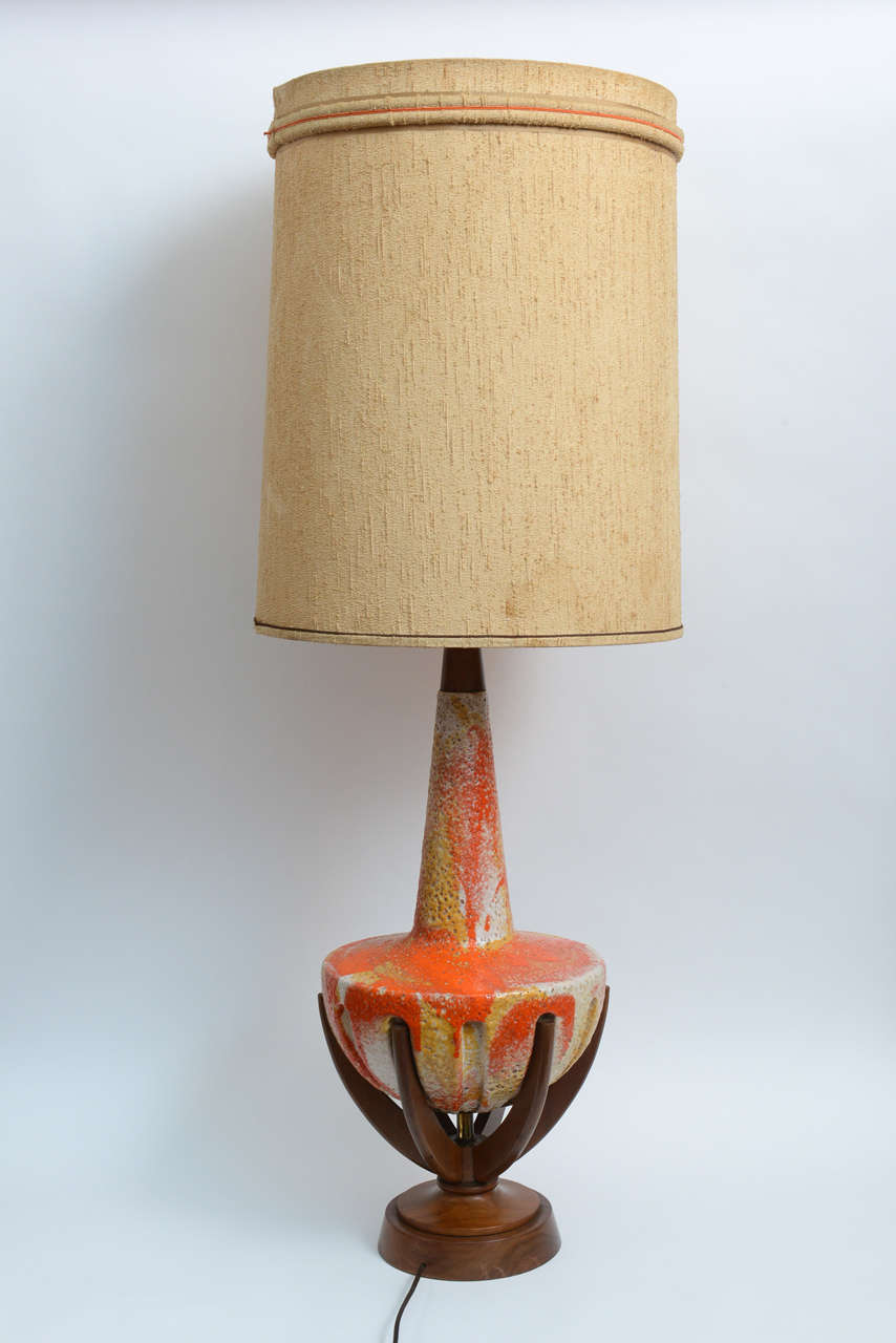 Really unusual and spectacular this fire color glaze lamp sitting on a tripod walnut base will fit any Mid-Century decor who is looking for a stunning accent full of joy. The shade is original. 
Lamp dimension: 30