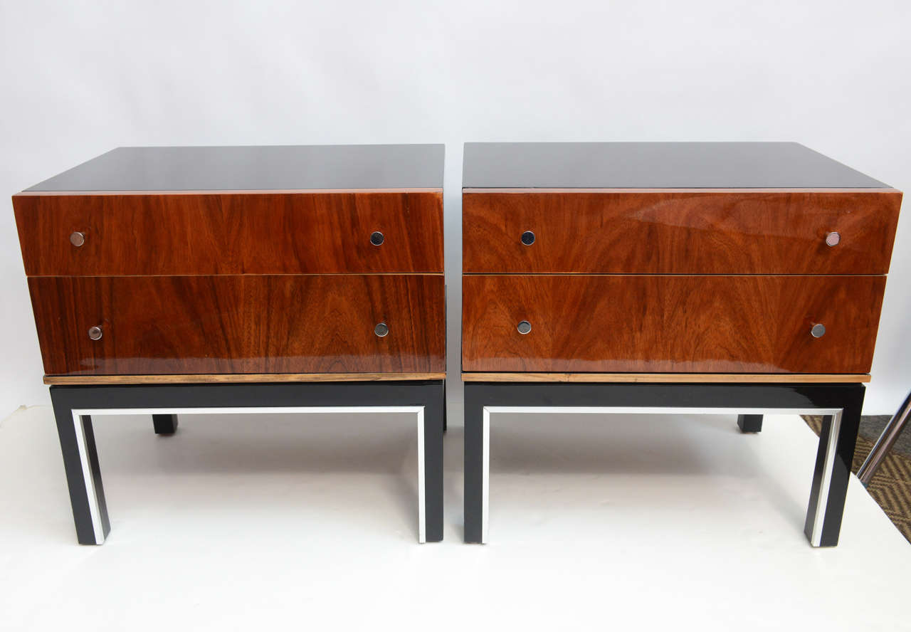 These nightstands are short, dark and handsome. Both feature freshly and beautifully lacquered. The two-drawer fronts have been refinished with a natural high gloss lacquered that display beautiful wood flames in warm tones. Original chrome tone