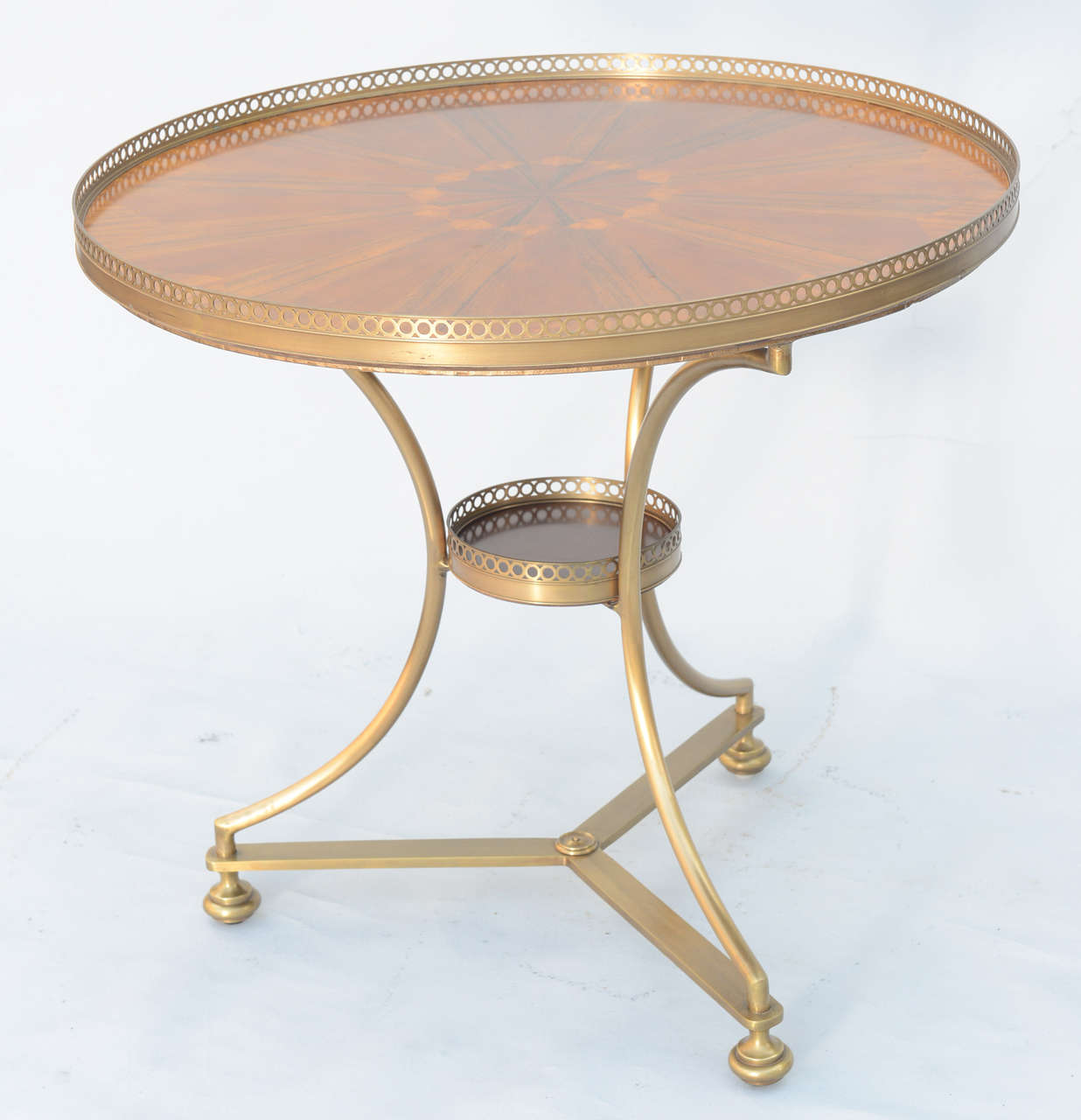 Bouillotte table, having beautifully inlaid top in starburst pattern, pierced gallery, raised on tripartite brass base centered with conforming shelf.

Stock ID: D9223