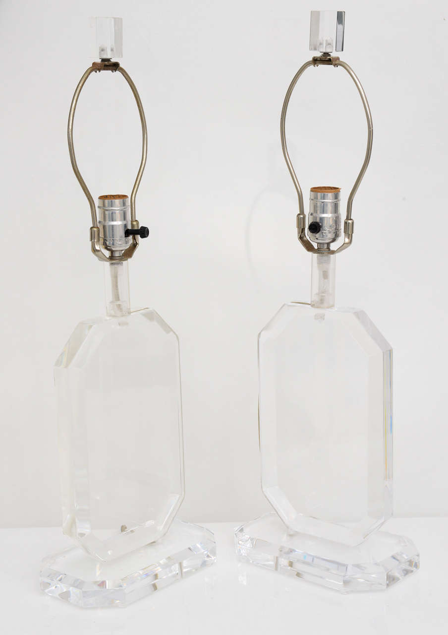 Pair of geometric shaped Lucite lamps in the style of Karl Springer. The lamps have matching Lucite finials.