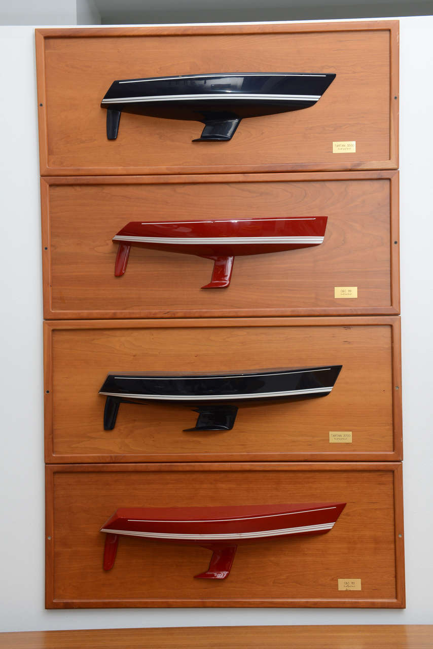 Group of four wood mounted half-hull racing boat models. Each boat type is labeled on a square engraved metal plaque.