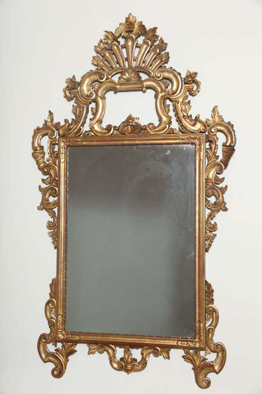 Rectangular mirror, of carved giltwood, having pierced pediment and surround with elaborate C-scroll, acanthus leaf and floral details.