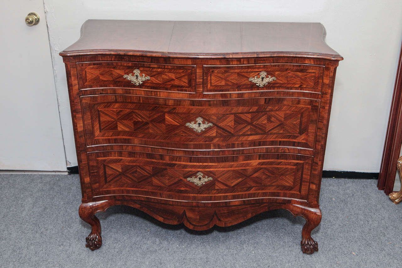 Superb, c. 1850, serpentine, four-drawer, parquetry commode inlaid with walnut, olive, fruit, and pear woods.  The whole sits atop a scrolling apron and petite, cabriole legs terminating in ball and claw feet.