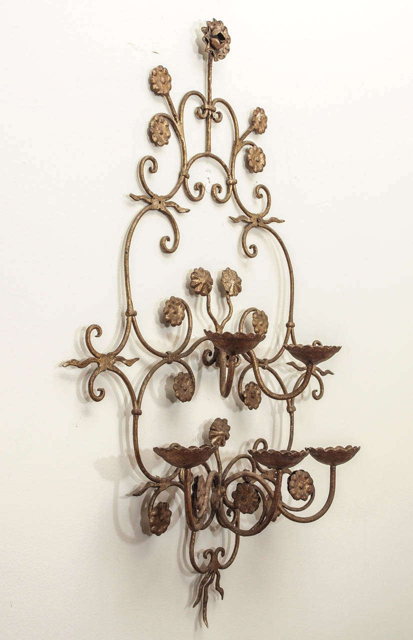 A five light wall sconce embellished with flowers and crimped candleholders or bobeches.