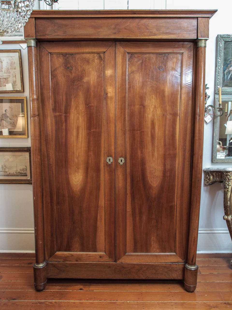 A two door armoire with simple, molded panels for the doors and sides, the doors flanked with bronze mounted, free-standing columns.  Slight bow to the columns, an appropriate condition for aging wood.  Doors of book matched wood.